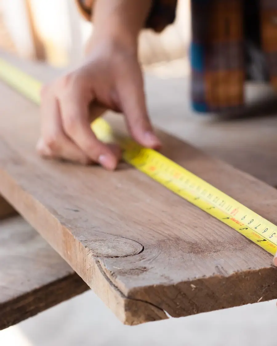 Artisan mesurant une planche au mètre ruban